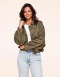 Fit mature woman wearing khaki faux-suede oversized bomber jacket, front three-quarter view