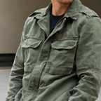 Man wearing the olive green Mason field jacket with the collar folded down, showing the chest flap pockets and zip front